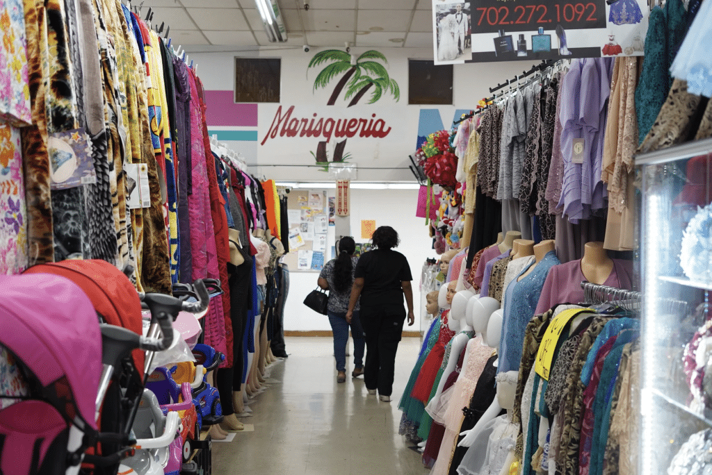 Interior image of two women walking through Eastern Indoor Swap Meet in Las Vegas with clothes on both sides